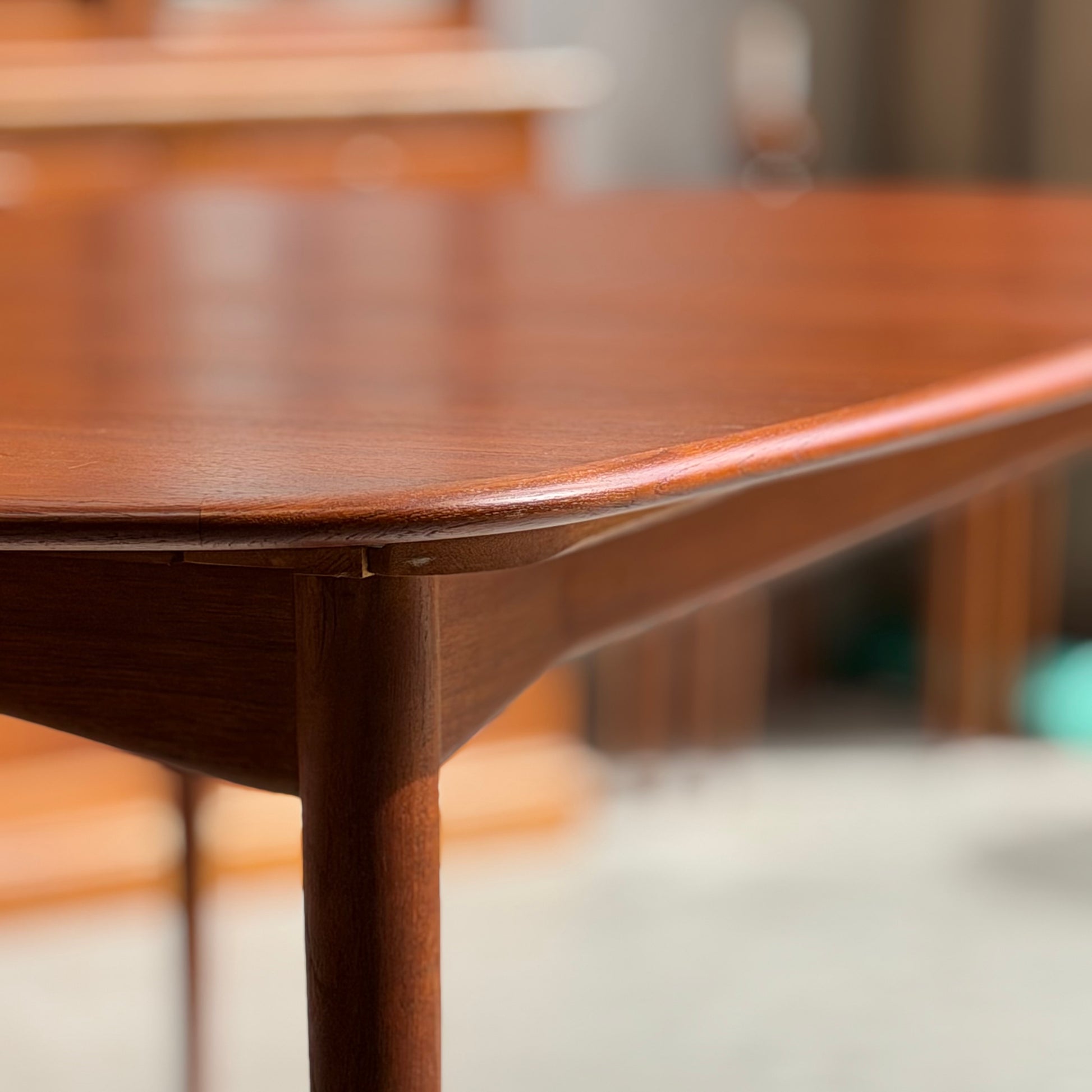 Close-up of the corner of a Fully Restored Parker No.92 D End Dining Table (Rediscover), highlighting its rounded edges, smooth finish, and mid-century modern craftsmanship in warm, natural light with a softly blurred background.
