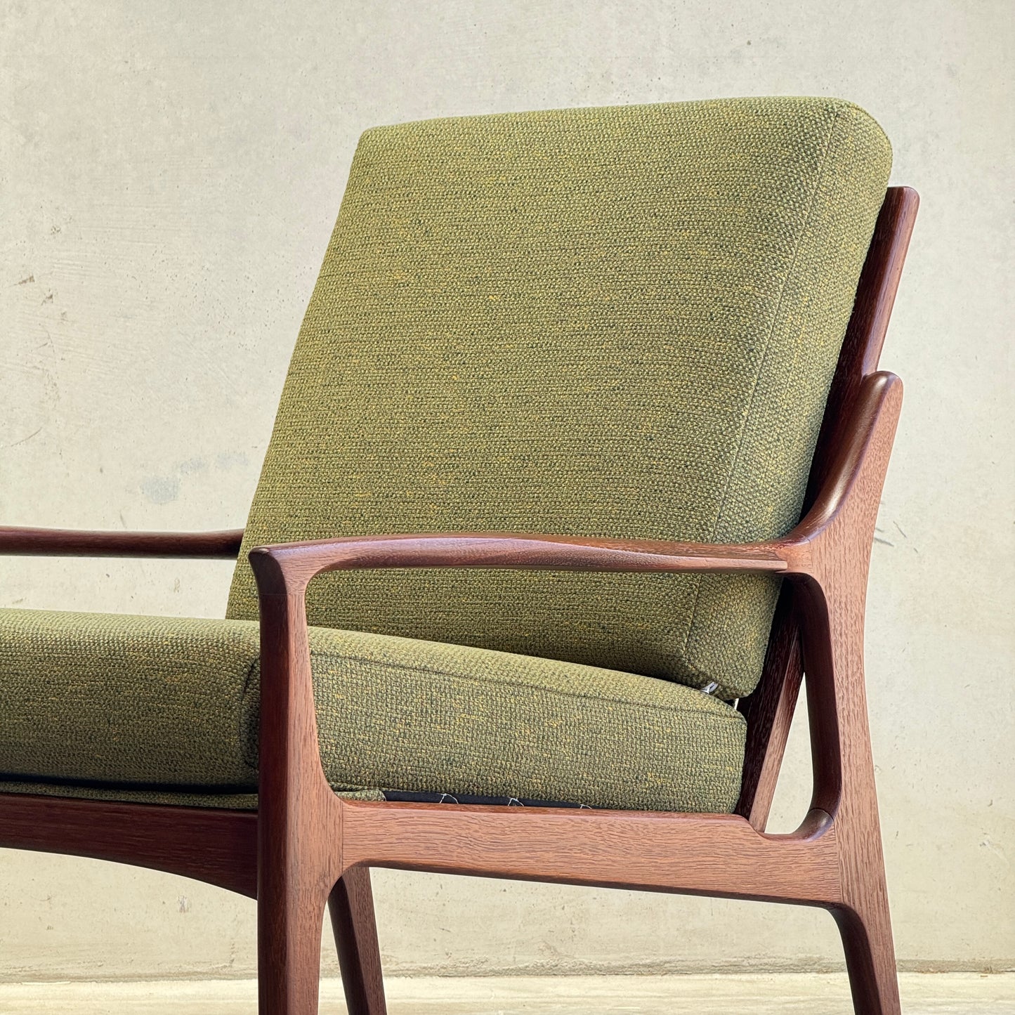 The Don Rex Armchair - Green Forest (Rediscover) features green upholstered cushions and a wooden frame, showcasing clean lines and minimalist Danish modernism against a light backdrop.