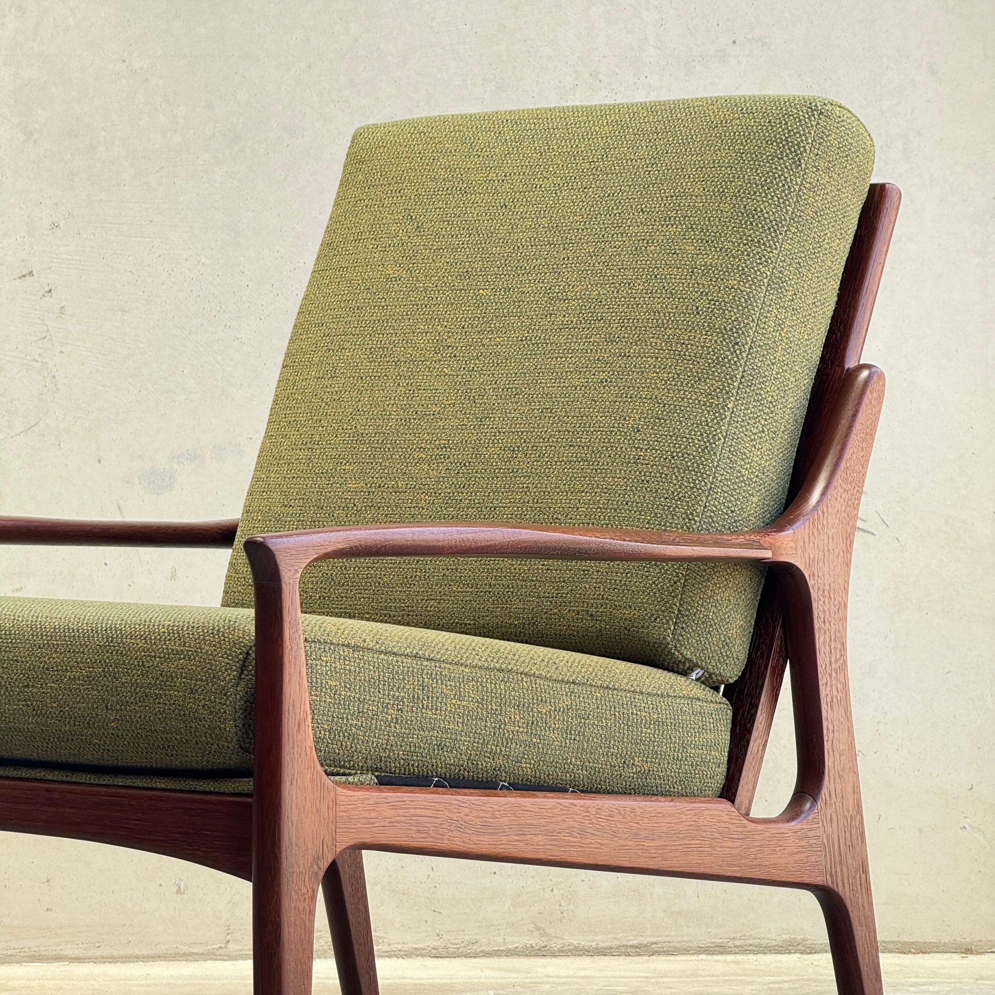 The Don Rex Armchair - Green Forest (Rediscover) features green upholstered cushions and a wooden frame, showcasing clean lines and minimalist Danish modernism against a light backdrop.