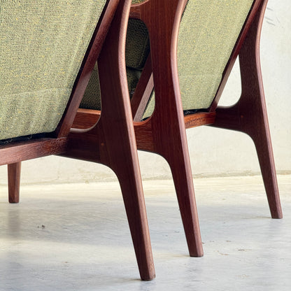 Close-up of the back and legs of two Don Rex Armchairs - Green Forest (Rediscover), upholstered in olive green, set on a light concrete floor against a plain wall—an elegant showcase of mid-century Australian design.