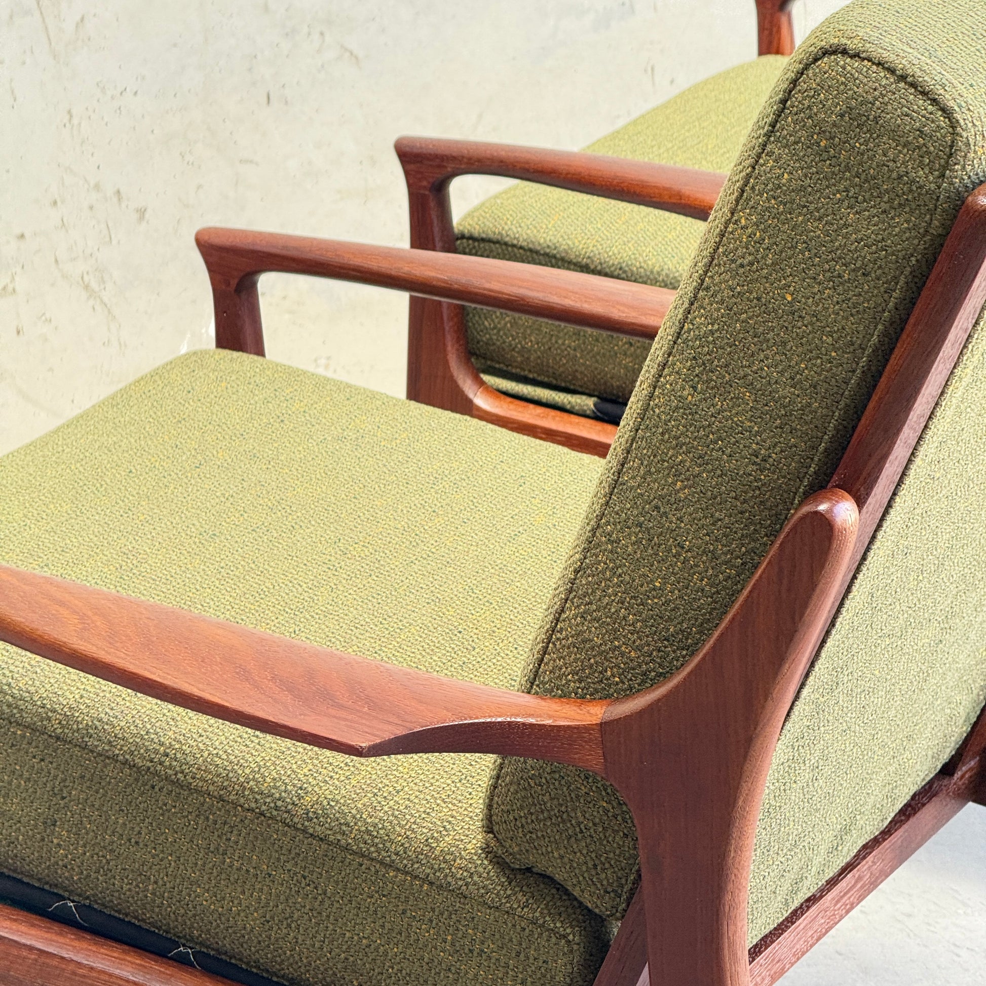 Close-up of the Don Rex Armchair - Green Forest (Rediscover), featuring Danish modernism with green textured upholstery and smooth, curved wooden arms and frame, set against a neutral background.
