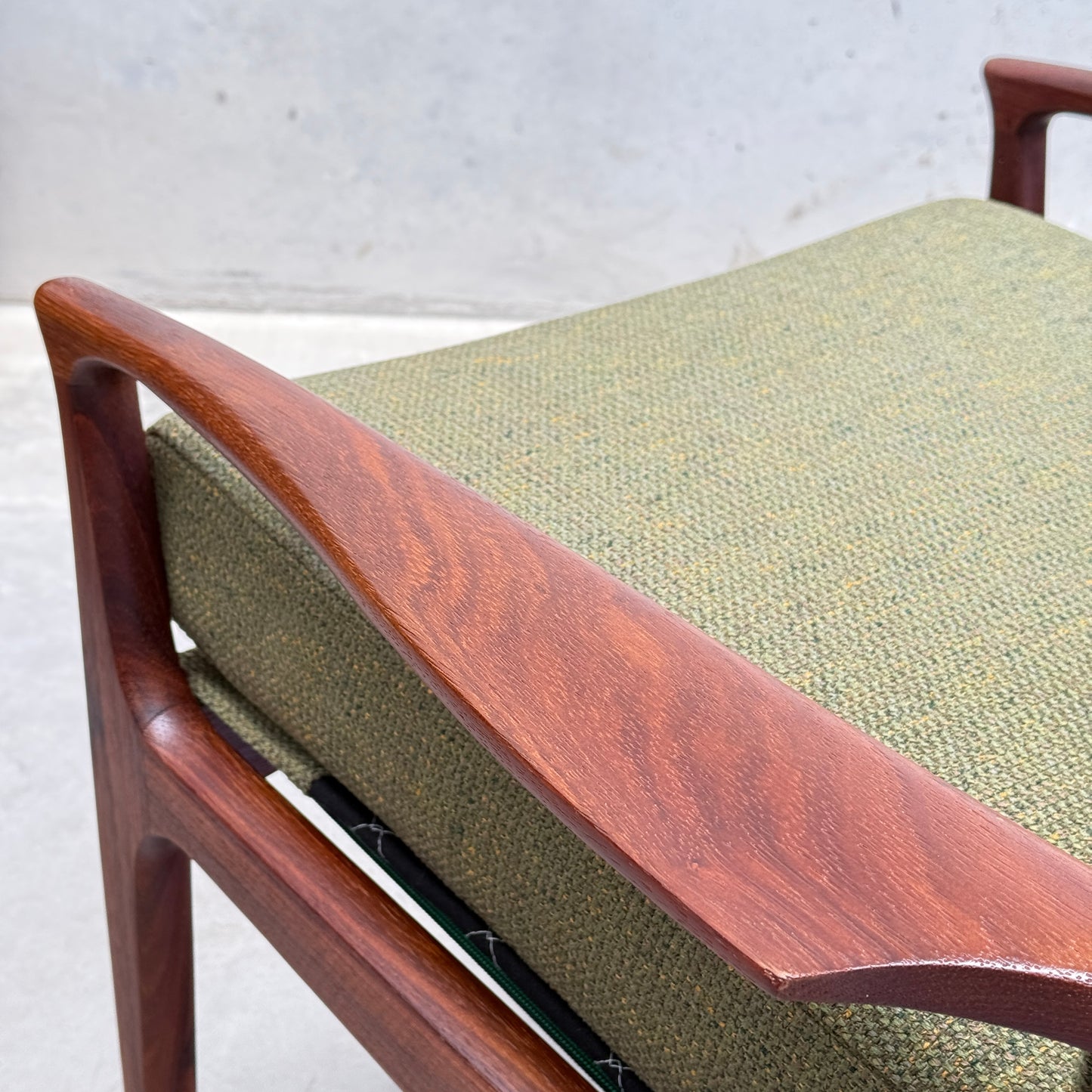Close-up of the Don Rex Armchair - Green Forest (Rediscover) highlights the smooth wooden armrest and textured green upholstery—timeless mid-century Australian style with Danish modern inspiration—set against a plain light gray background.