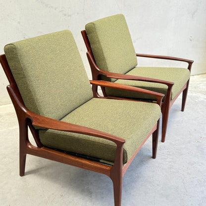 Two Don Rex Armchair - Green Forest (Rediscover) seats with green upholstery and wooden frames sit side by side on a light gray floor against a plain, light-colored wall.