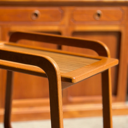 A close-up of the Mid-Century Noblett Drinks Trolley with its warm-toned wood, removable tray, and original castors evokes the timeless Noblett style, reminiscent of classic wooden furnishings.