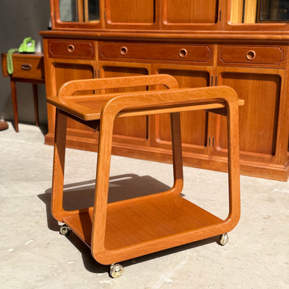 The Mid-Century Noblett Drinks Trolley—featuring a removable tray and original castors—stands sunlit before matching Noblett pieces, epitomizing mid-century style.