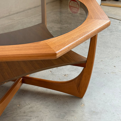 Close-up of the Octagonal Mid Century Coffee Table by Kalmar Furniture, featuring smoked glass top, hardwood frame, magazine rack shelf, and angular legs—showcasing elegant Australian mid-century design on a concrete floor.
