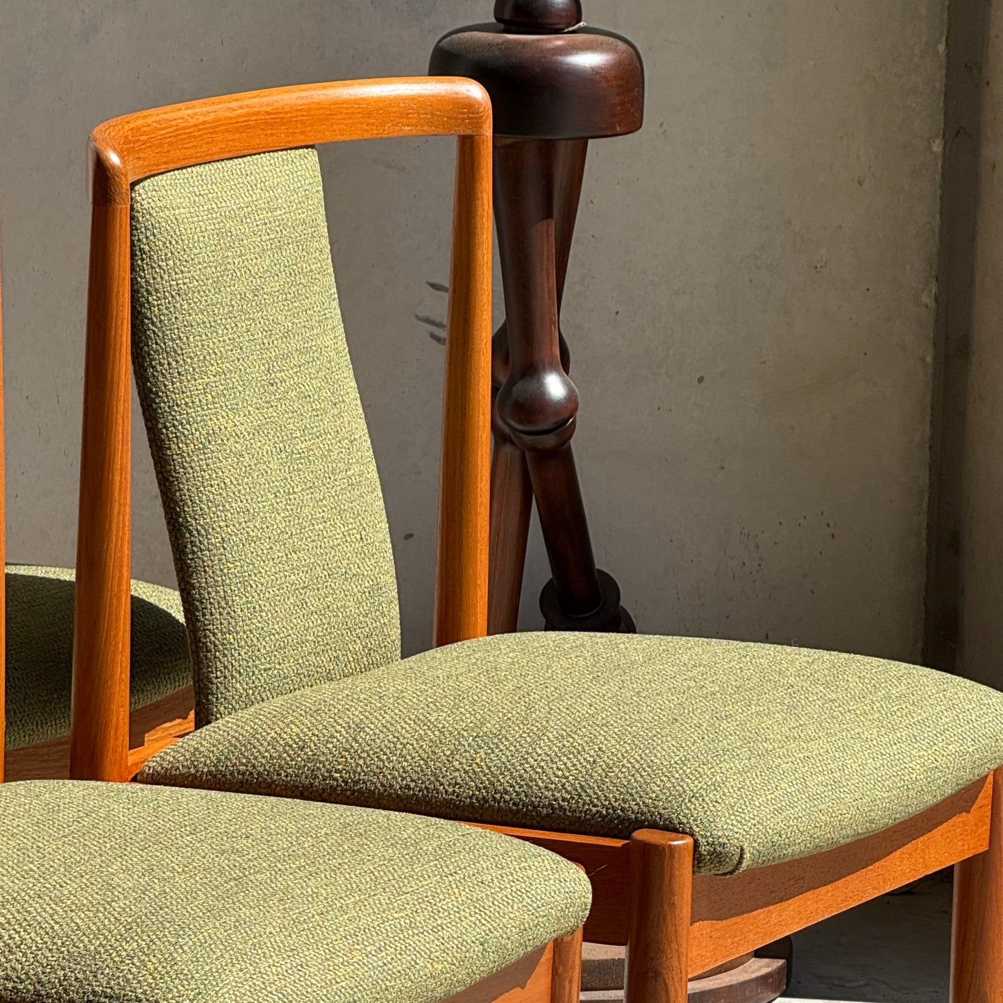 Two fully restored Parker T-Back Number 88 dining chairs in forest green, part of a set of six, feature wooden frames and are shown in sunlight beside a dark pedestal table against a plain wall.