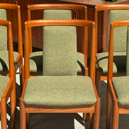 Six Fully Restored Parker T-Back Number 88 Dining Chairs in forest green upholstery are arranged in rows with sunlight casting shadows, while a wooden table stands in the background.