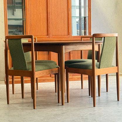 Six fully restored Parker T-Back Number 88 dining chairs in forest green (Rediscover) surround a matching rectangular wooden table, while a glass-front cabinet completes the mid-century modern look on a concrete floor.