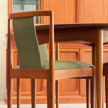 A close-up of a fully restored Parker T-Back Number 88 dining chair in forest green upholstery from the set of 6 by Rediscover, positioned beside a matching table and in front of a paneled wooden cabinet.