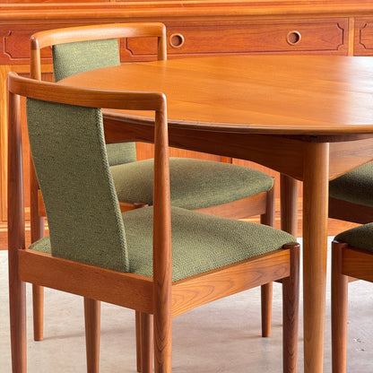 A close-up of fully restored Parker T-Back Number 88 Dining Chairs Set of 6 in forest green, paired with a matching dining table on a light floor, with a wooden sideboard in the background.
