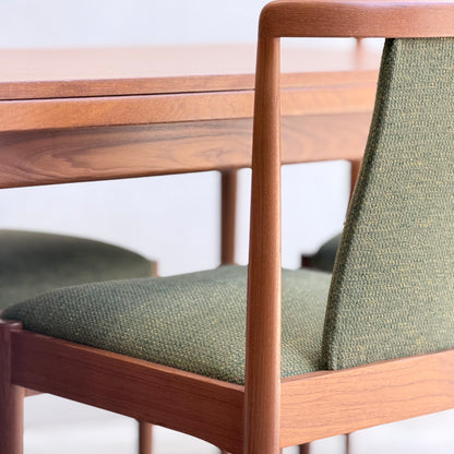 A close-up of the Fully Restored Parker Dining Suite 5 Piece - Forest Green (Rediscover) highlights its Scandinavian-inspired mid-century modern design, smooth wood grain, and green upholstered seats and backrests.