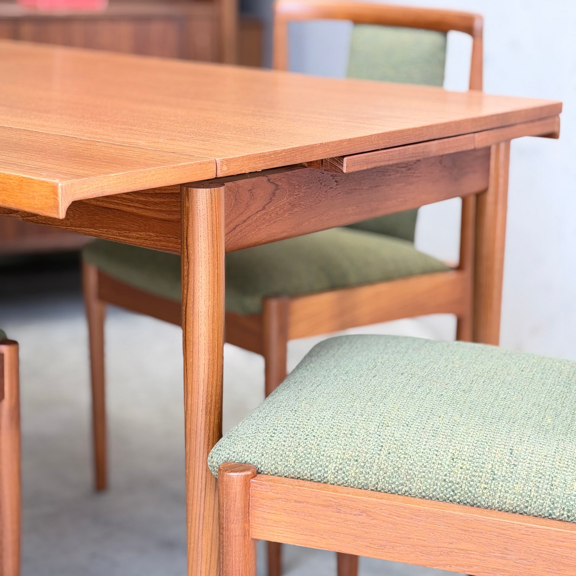 Close-up of the Fully Restored Parker Dining Suite 5 Piece - Forest Green by Rediscover, showcasing its Scandinavian-inspired design with rounded edges, green upholstered seats, and wooden frames in a bright indoor setting.