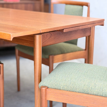 Close-up of the Fully Restored Parker Dining Suite 5 Piece - Forest Green by Rediscover, showcasing its Scandinavian-inspired design with rounded edges, green upholstered seats, and wooden frames in a bright indoor setting.