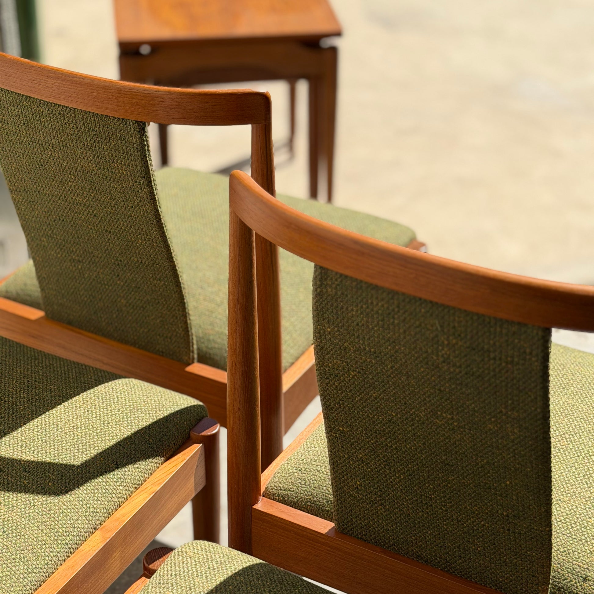 Four fully restored Parker T-Back Number 88 dining chairs in forest green (Rediscover) are displayed in sunlight, with a small wooden table behind them on a light floor, highlighting their classic mid-century modern charm.