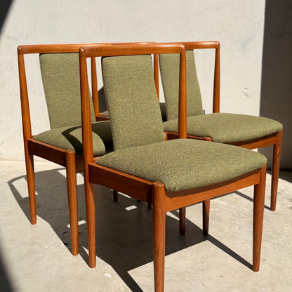 A set of four fully restored Parker T-Back Number 88 dining chairs in forest green (Rediscover) are grouped on a sunlit, light concrete floor against a plain wall.