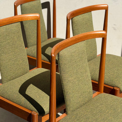 A set of four fully restored Parker T-Back Number 88 dining chairs in forest green (Rediscover) are arranged together, sunlight highlighting their mid-century modern frames and curved backrests.
