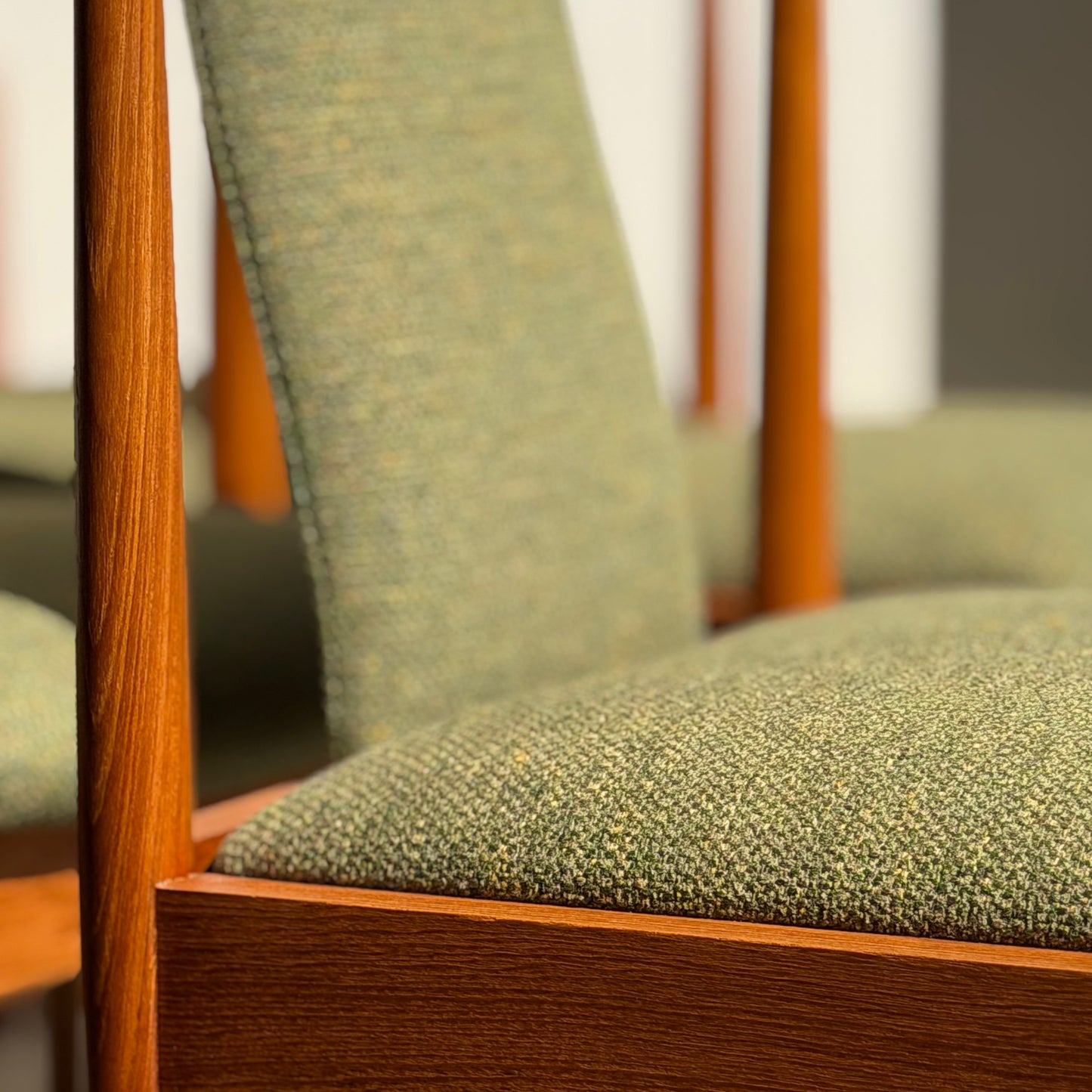 Close-up of a fully restored Parker T-Back Number 88 Dining Chair from the Rediscover set of 4 in forest green, featuring textured upholstery and a wooden frame—an iconic mid-century modern design bathed in warm sunlight.