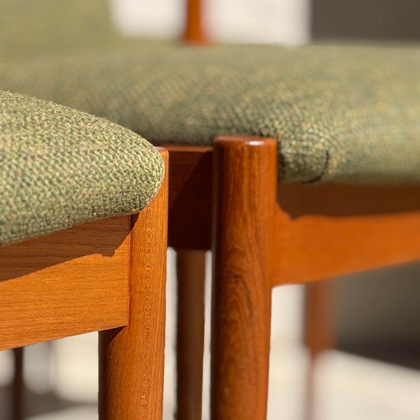 Close-up of two Fully Restored Parker T-Back Number 88 Dining Chairs (Set of 4) in forest green upholstery. Teak frames highlight mid-century modern style, with sunlight emphasizing the contrast of wood and fabric.