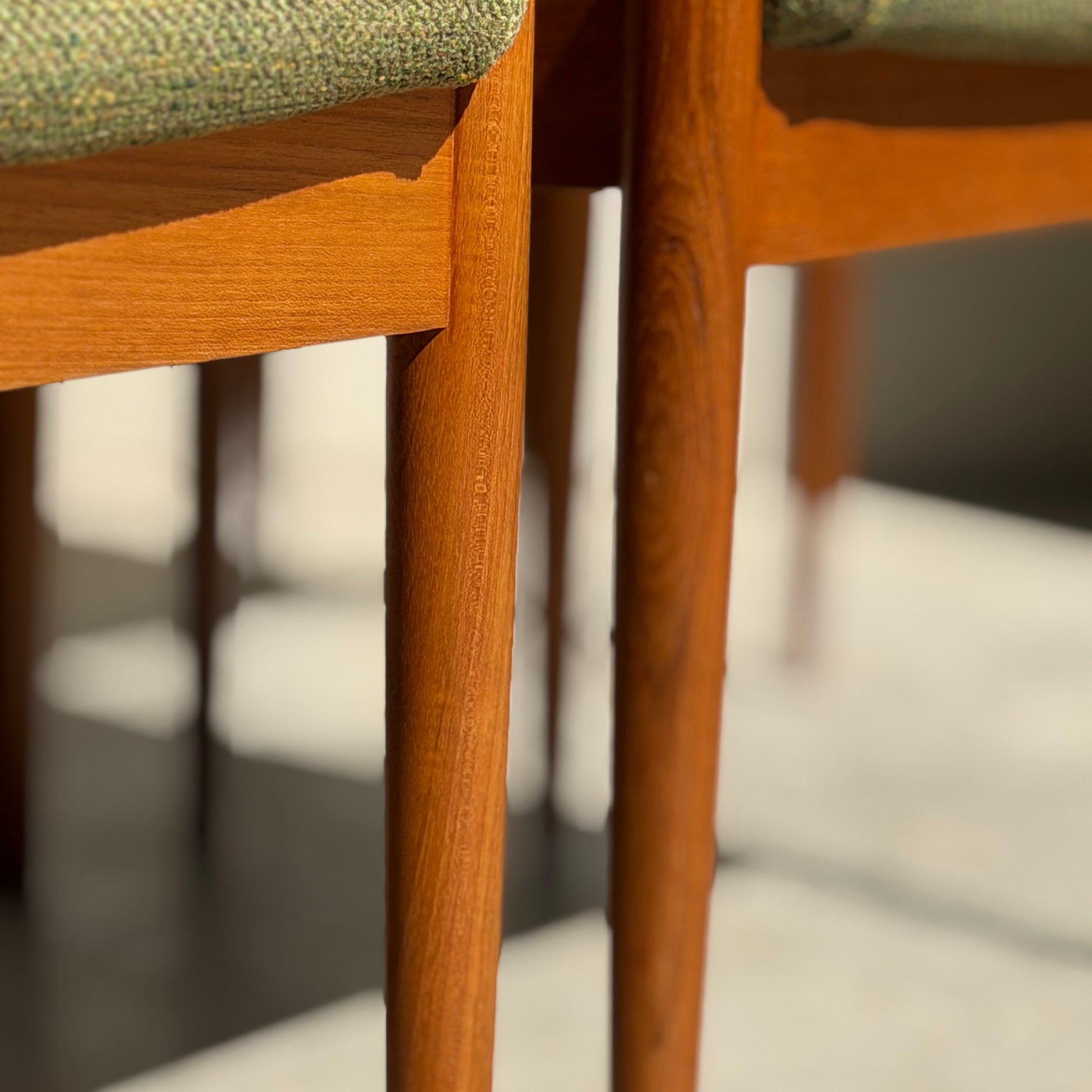 Close-up of the fully restored Parker T-Back Number 88 Dining Chairs Set of 4 - Forest Green (Rediscover), showcasing elegant wooden legs, green upholstery, and mid-century modern design in sunlight with soft floor shadows.