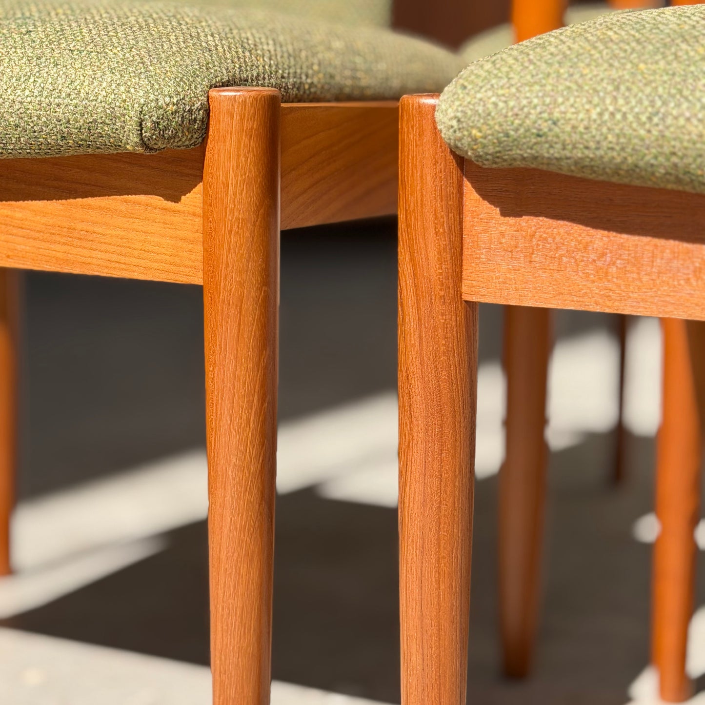 Close-up of fully restored Parker T-Back Number 88 Dining Chair legs with forest green upholstery, sunlight highlighting the smooth wood and textured fabric—showcasing true mid-century modern style.