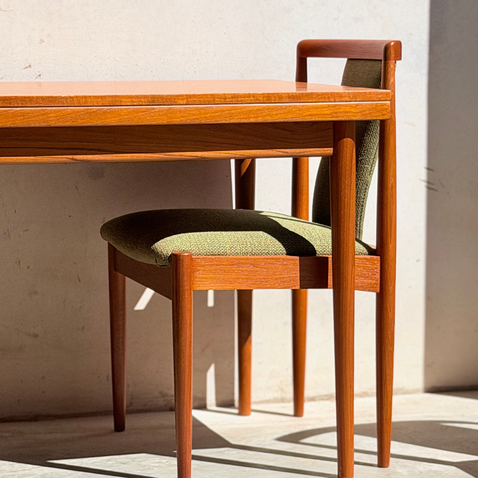 A set of four Parker 88 T Back Chairs, available for professional restoration with a 25% non-refundable deposit, features green upholstery and minimalist mid-century design. Sunlight highlights the chairs against a light wall and floor.