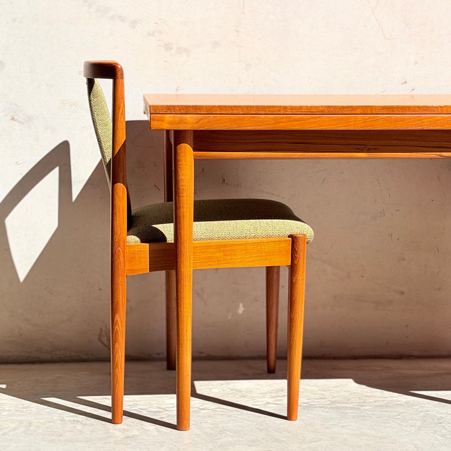The Fully Restored Parker Dining Suite 5 Piece - Forest Green (Rediscover) features Scandinavian-inspired wooden chairs with green cushions and a matching table, set against a light wall for a classic mid-century modern vibe.