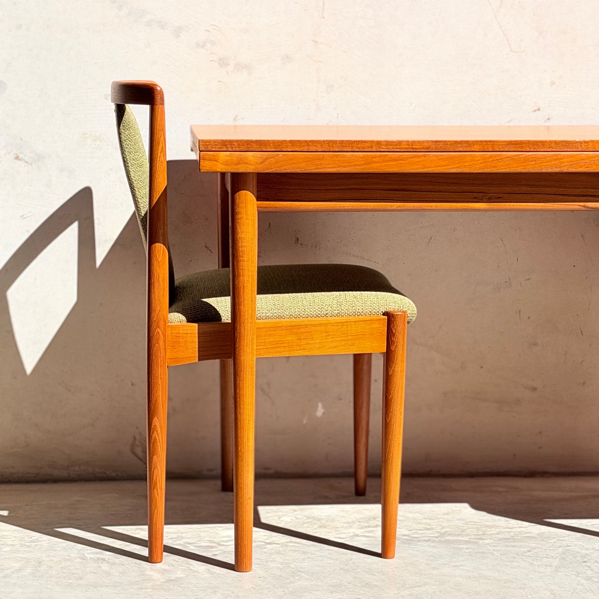 The Fully Restored Parker Dining Suite 5 Piece - Forest Green (Rediscover) features Scandinavian-inspired wooden chairs with green cushions and a matching table, set against a light wall for a classic mid-century modern vibe.