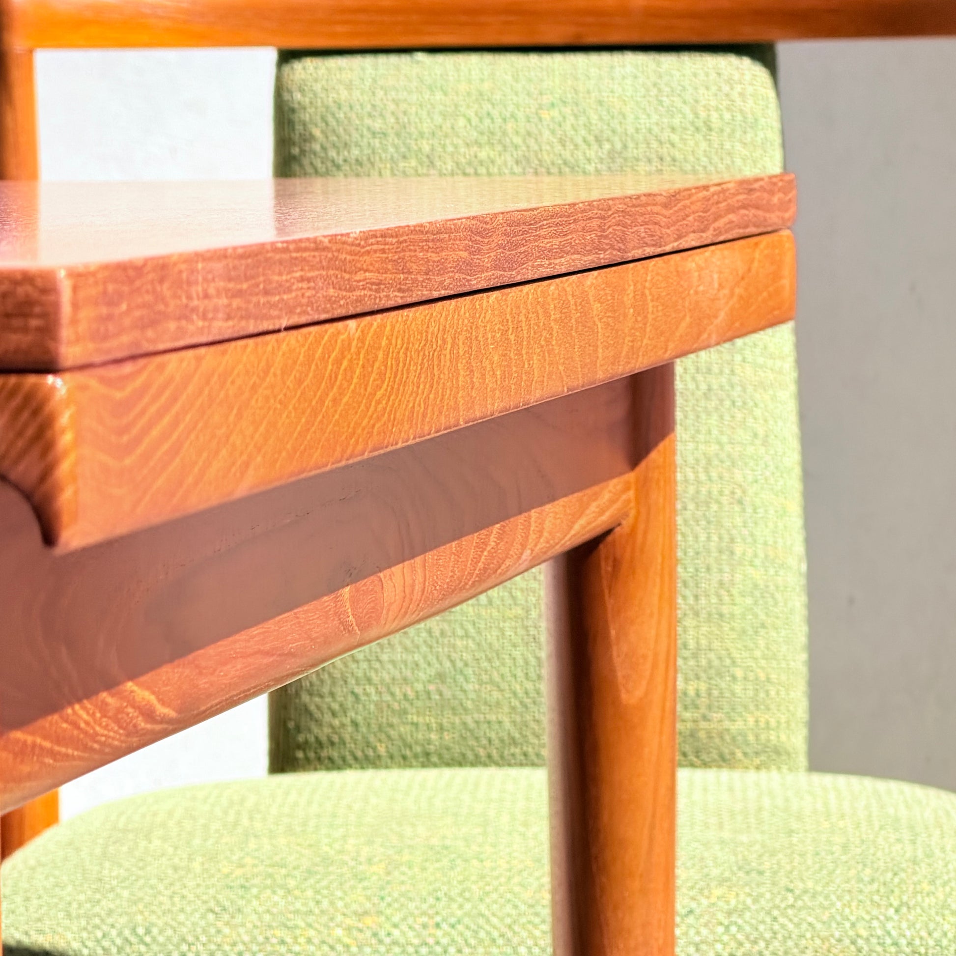 Close-up of the Fully Restored Parker Dining Suite 5 Piece - Forest Green: sunlight highlights the wood grain and forest green upholstery texture on the table and chair, showcasing their mid-century modern design.