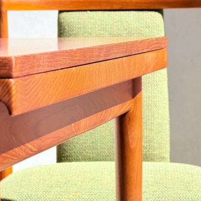 Close-up of the Fully Restored Parker Dining Suite 5 Piece - Forest Green: sunlight highlights the wood grain and forest green upholstery texture on the table and chair, showcasing their mid-century modern design.