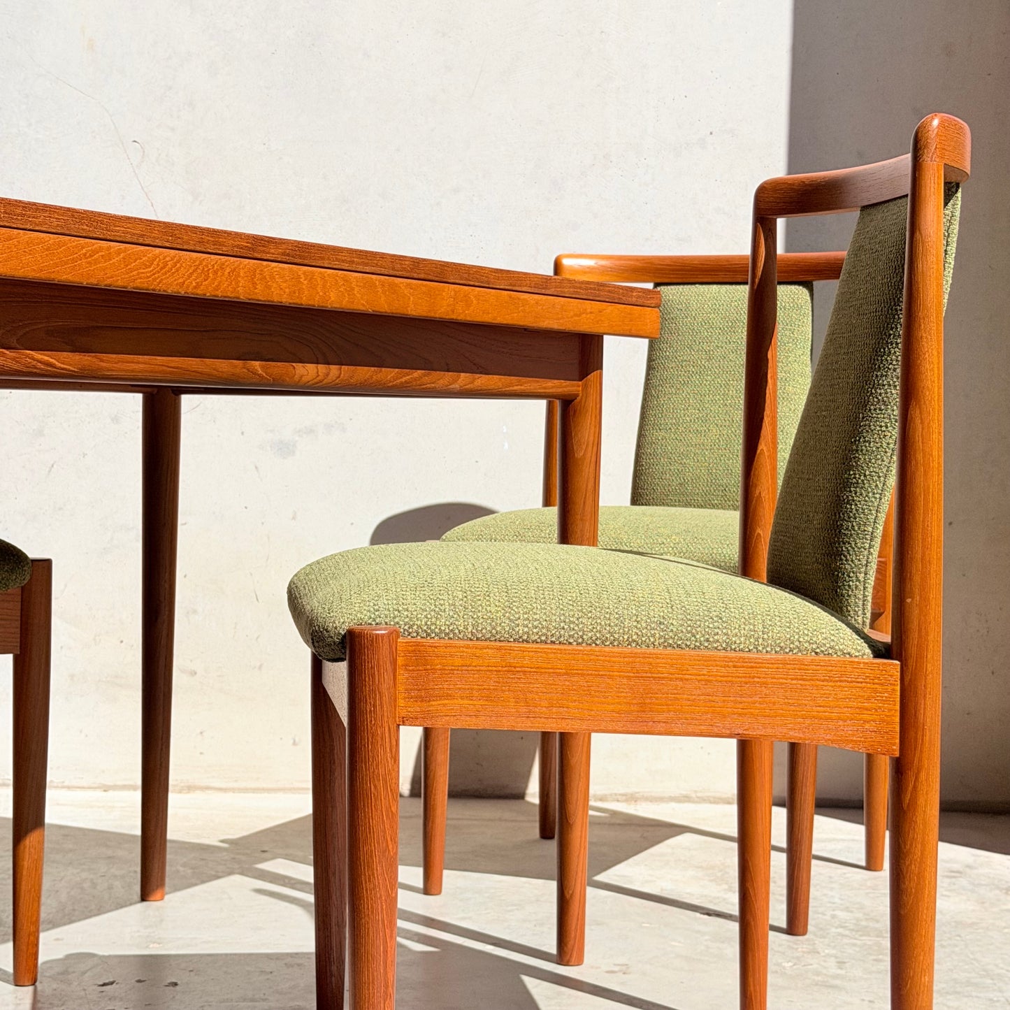 The Fully Restored Parker Dining Suite 5 Piece – Forest Green features two Scandinavian-style wooden chairs with green upholstery and a matching table, all set in a sunlit, neutral mid-century modern dining space.