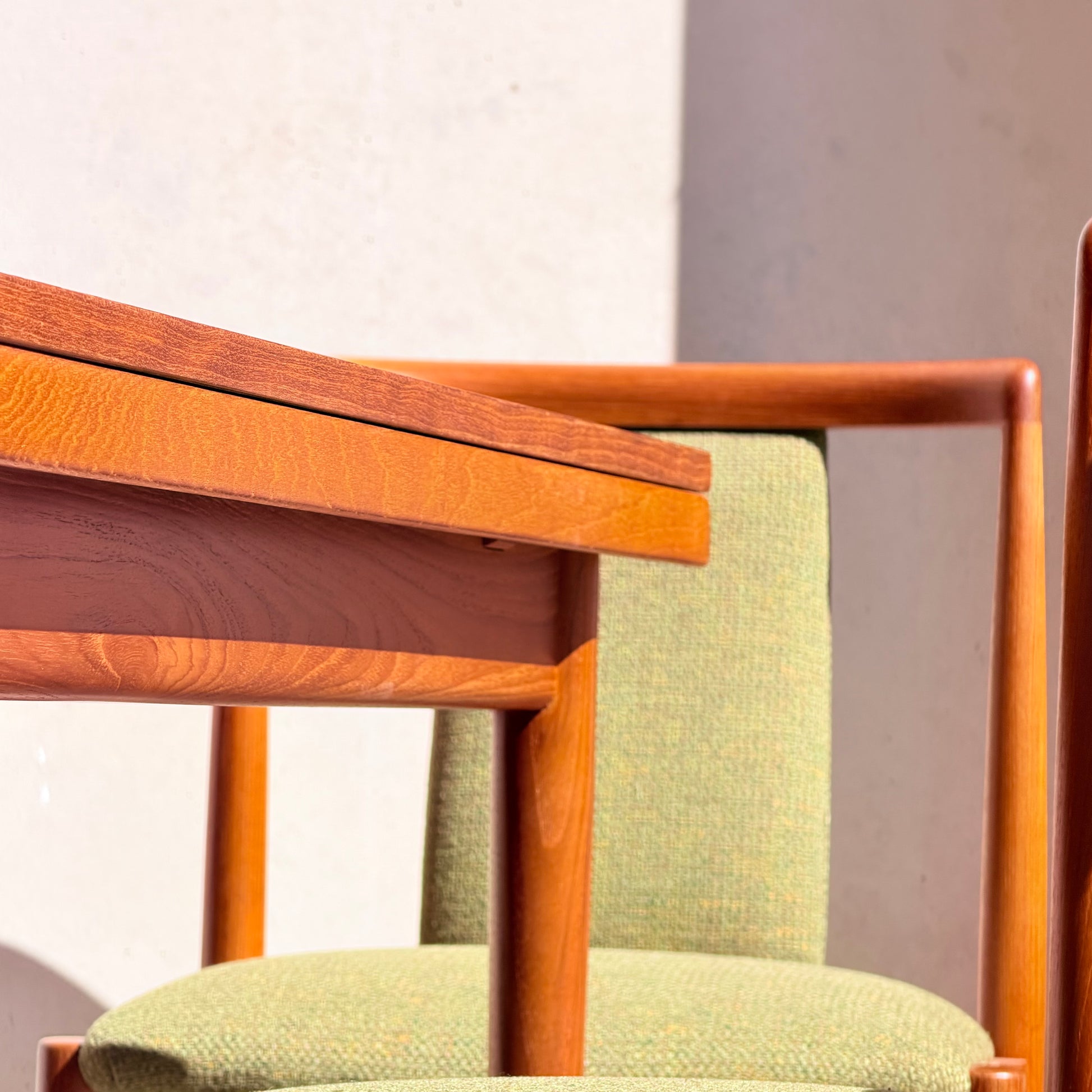 Close-up of the Fully Restored Parker Dining Suite 5 Piece - Forest Green (Rediscover), featuring a wooden table and chairs with green upholstery, sunlit and casting soft shadows—a perfect Scandinavian-inspired, mid-century modern set.