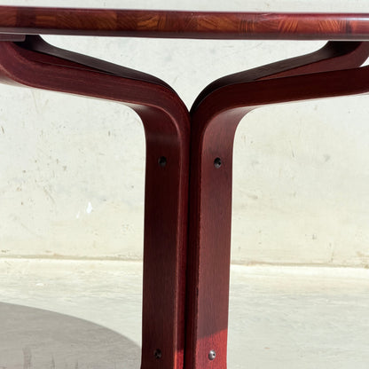 Close-up of the solid wood base and curved, dark reddish legs of the Joe Rufenacht Designer Round Dining Table – Rare Mid-Century Gem in Solid Wood (Refine), joined with screws against a light-colored concrete background.