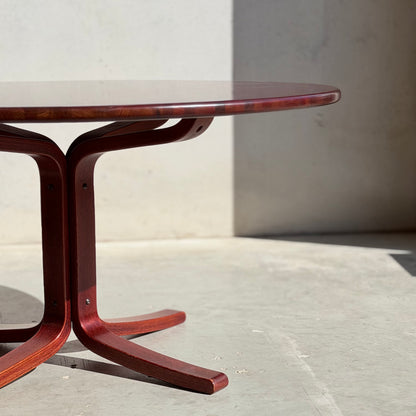 The Joe Rufenacht Designer Round Dining Table – Rare Mid-Century Gem in Solid Wood (Refine) features a glossy finish and sculpted base, standing on a light concrete floor with sunlight casting graceful shadows nearby.