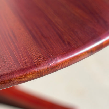 Close-up of the Joe Rufenacht Designer Round Dining Table – a rare mid-century gem in solid wood. The reddish-brown polished finish showcases the wood grain, with a small scratch visible on the rounded edge.