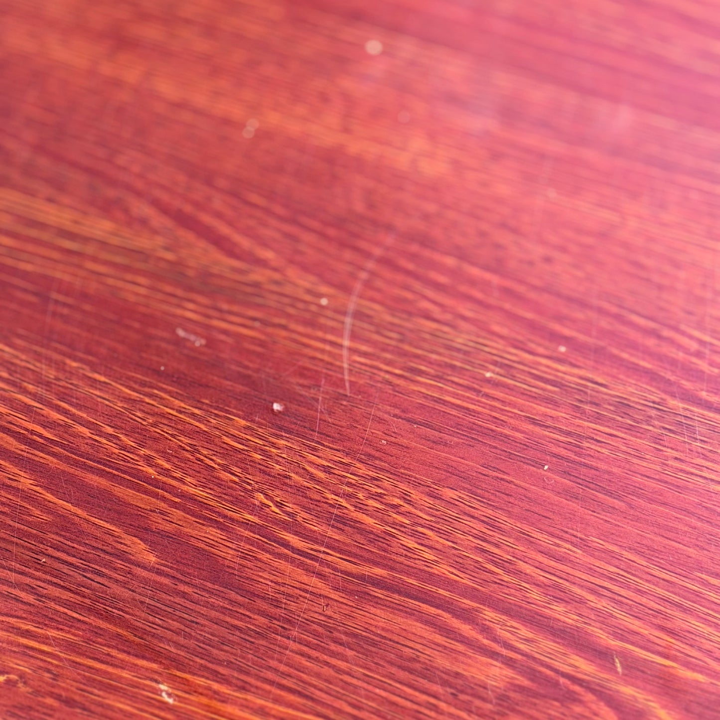 Close-up of the solid wood surface on a Joe Rufenacht Designer Round Dining Table – Rare Mid-Century Gem, showing visible grain, natural variations, and subtle marks highlighted by the lighting.