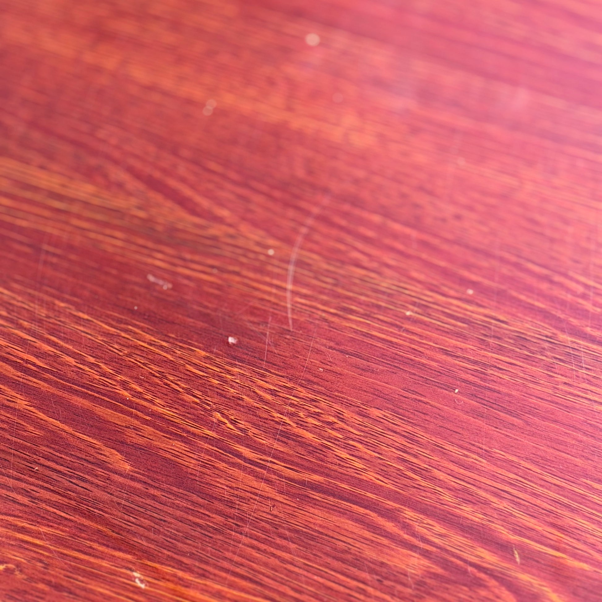Close-up of the solid wood surface on a Joe Rufenacht Designer Round Dining Table – Rare Mid-Century Gem, showing visible grain, natural variations, and subtle marks highlighted by the lighting.