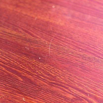 Close-up of the solid wood surface on a Joe Rufenacht Designer Round Dining Table – Rare Mid-Century Gem, showing visible grain, natural variations, and subtle marks highlighted by the lighting.