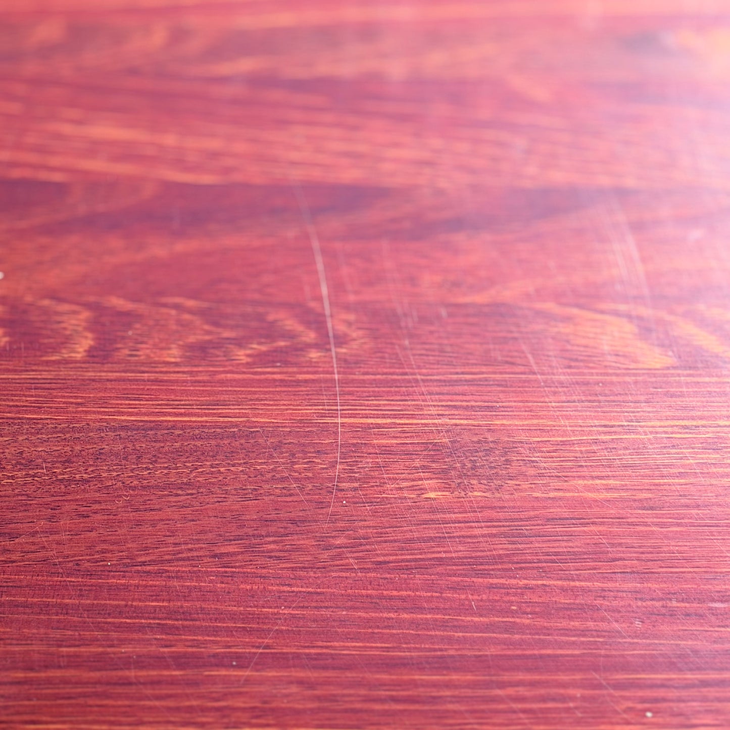 A close-up of the Joe Rufenacht Designer Round Dining Table—this rare mid-century gem in solid wood features a reddish-brown hue, visible grain, and subtle marks that highlight its refined craftsmanship and unique character.
