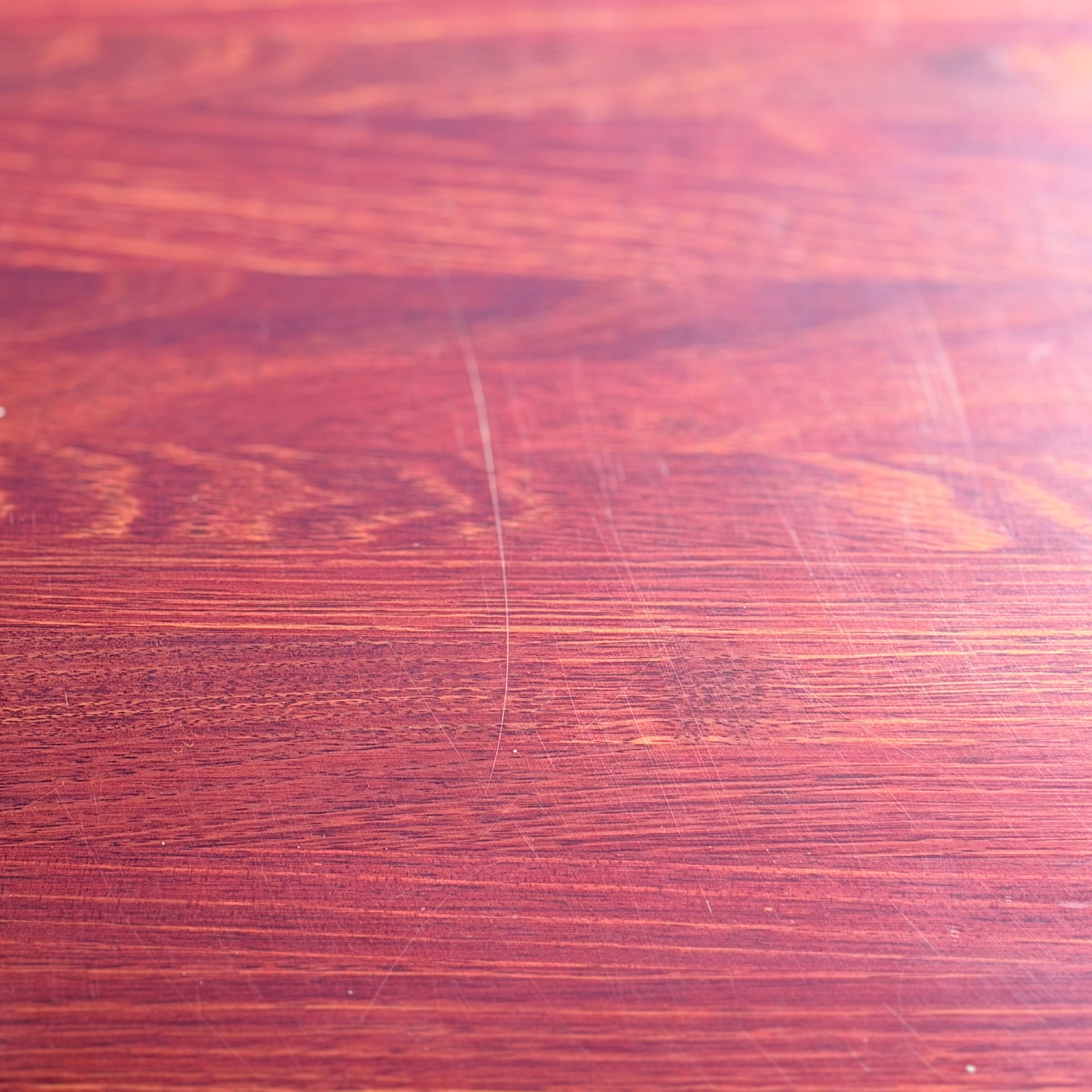 A close-up of the Joe Rufenacht Designer Round Dining Table—this rare mid-century gem in solid wood features a reddish-brown hue, visible grain, and subtle marks that highlight its refined craftsmanship and unique character.