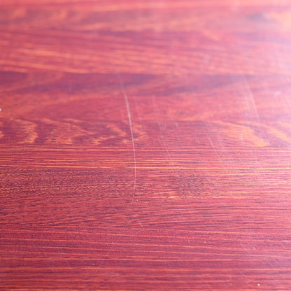 A close-up of the Joe Rufenacht Designer Round Dining Table—this rare mid-century gem in solid wood features a reddish-brown hue, visible grain, and subtle marks that highlight its refined craftsmanship and unique character.