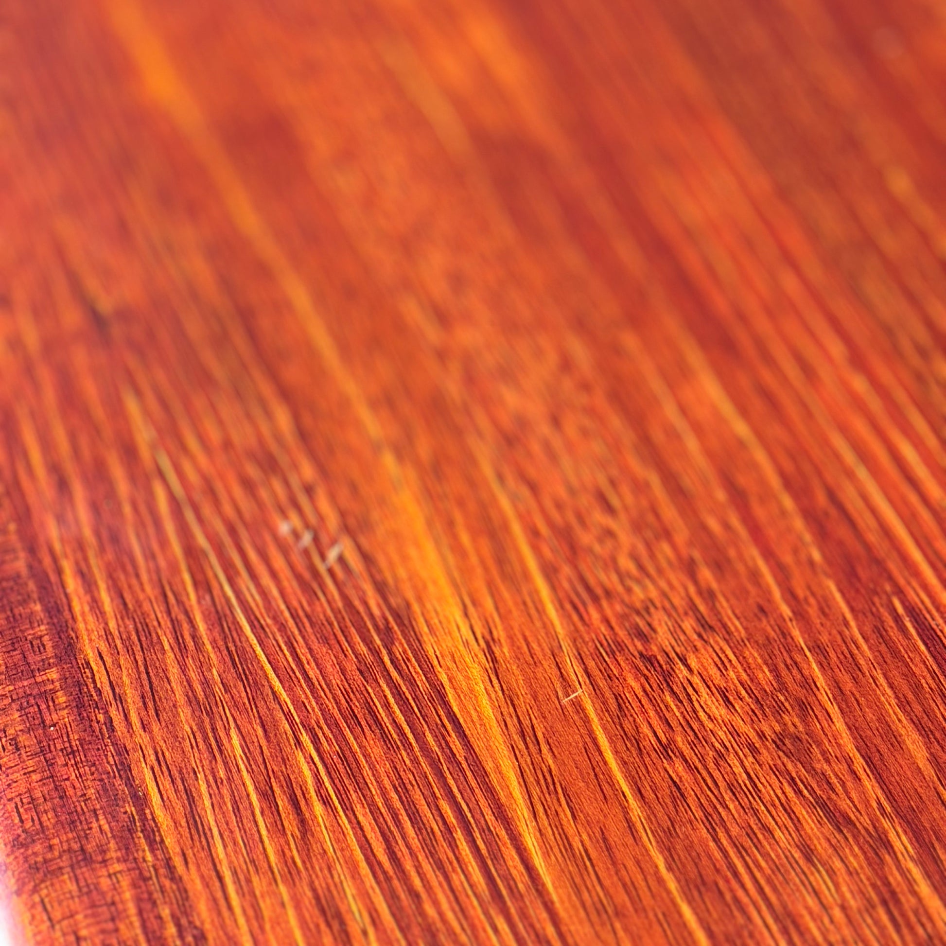 Close-up of the Joe Rufenacht Designer Round Dining Table’s polished solid wood surface, showing warm reddish-brown and golden grain patterns. Light enhances the natural texture of this rare mid-century gem.