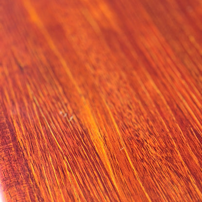 Close-up of the Joe Rufenacht Designer Round Dining Table’s polished solid wood surface, showing warm reddish-brown and golden grain patterns. Light enhances the natural texture of this rare mid-century gem.