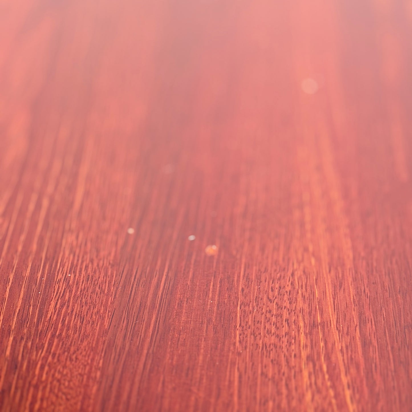 Close-up of the smooth, reddish-brown solid wood surface of the Joe Rufenacht Designer Round Dining Table—a rare mid-century gem—showcasing elegant grain and subtle texture that evoke refined craftsmanship.