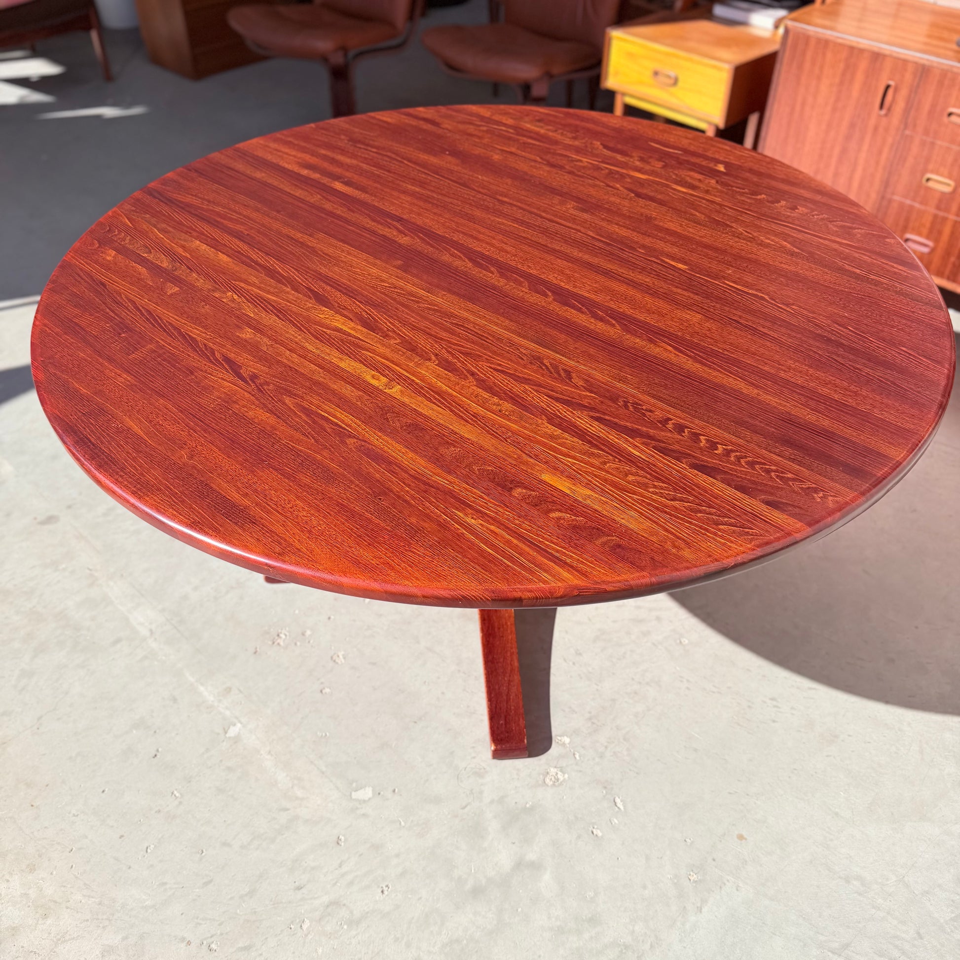 The Joe Rufenacht Designer Round Dining Table – Rare Mid-Century Gem in Solid Wood (Refine) features a rich reddish-brown finish and stands on a light floor, complemented by mid-century modern furniture for timeless appeal.