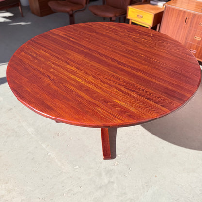 The Joe Rufenacht Designer Round Dining Table – Rare Mid-Century Gem in Solid Wood (Refine) features a rich reddish-brown finish and stands on a light floor, complemented by mid-century modern furniture for timeless appeal.
