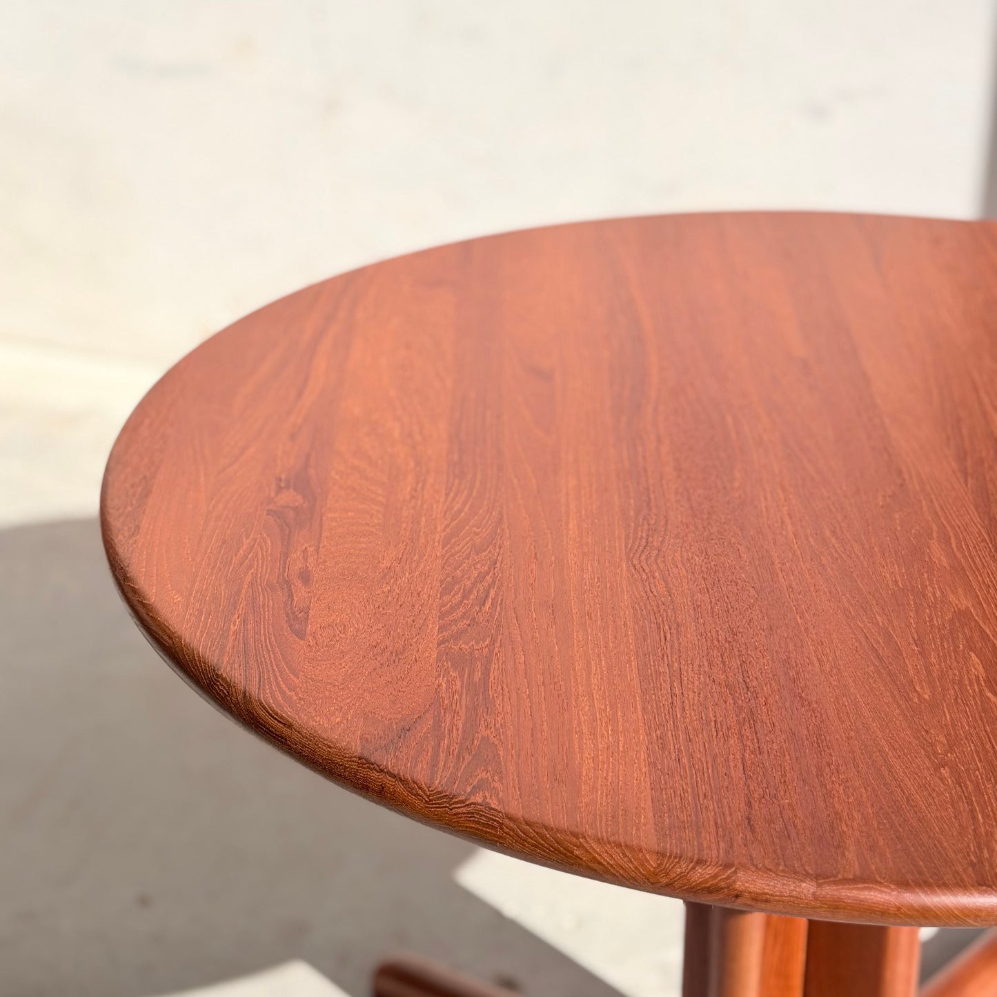 A close-up of the Fully Restored Solid Teak Danish Dining Table (Rediscover), featuring a smooth, polished surface and visible wood grain, set against a light, plain background.