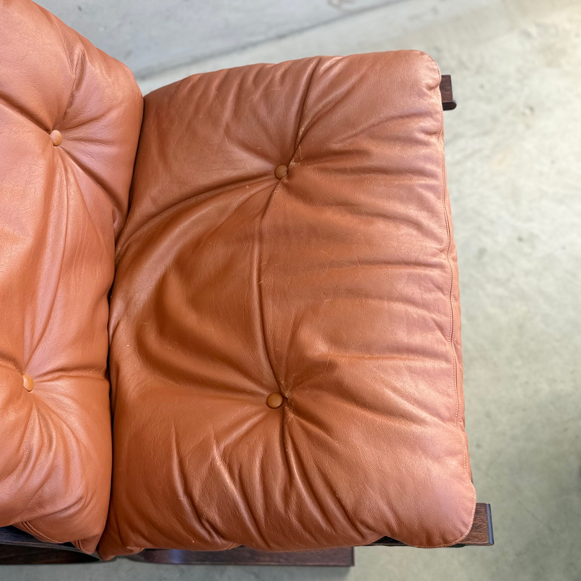 Close-up of two tufted, tan leather cushions on the Signature Vintage Ingmar Relling Siesta Set’s lounge chairs, showcasing classic creases and button details found in Scandinavian mid-century design.