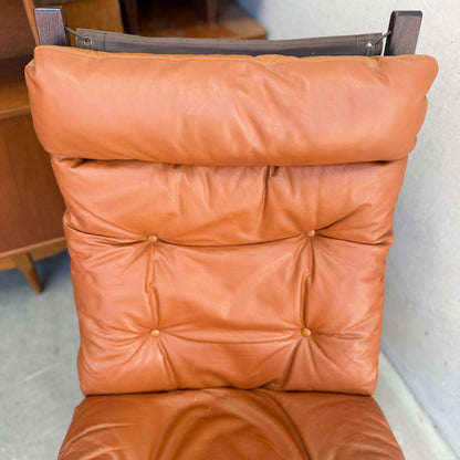 A close-up of the Signature Vintage Ingmar Relling Siesta Set’s lounge chair, featuring caramel leather upholstery and wooden frame, highlights the cushioned backrest and seat reminiscent of iconic mid-century design.