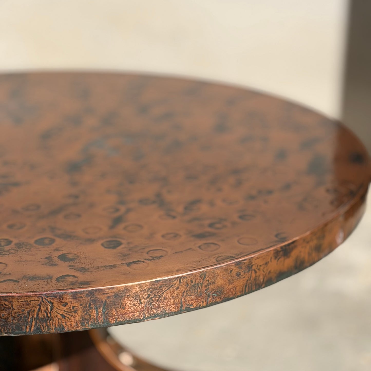 A close-up of the Vintage Louis Berczi Hammered Copper Round Coffee Table – Rare Australian Collectible (Revive), showcasing its hand-hammered, textured copper surface with circular and mottled patterns. The background is softly blurred.
